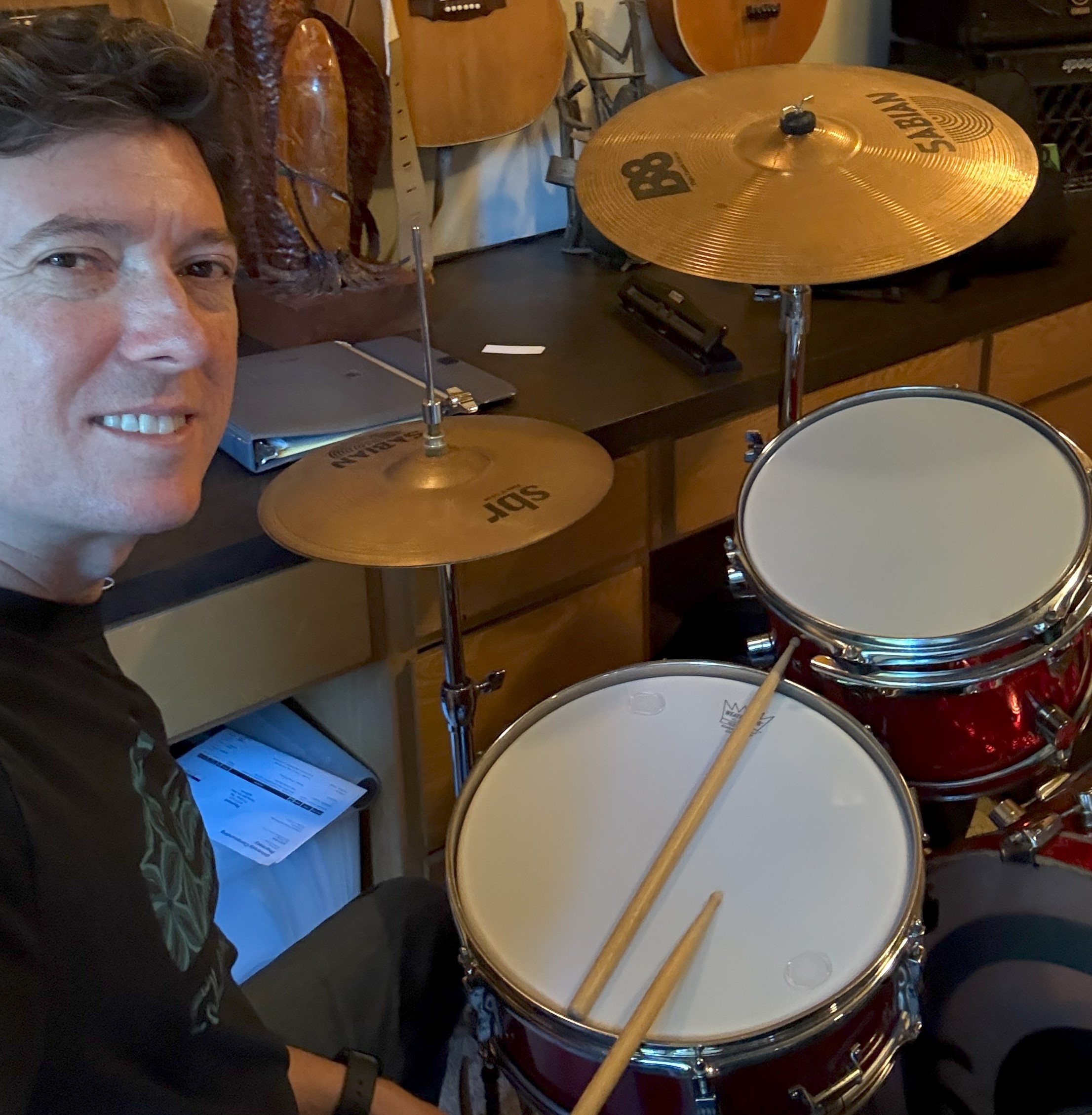 A pair of sunglasses and a microphone placed against the backdrop of a vibrant sunset over a beach.