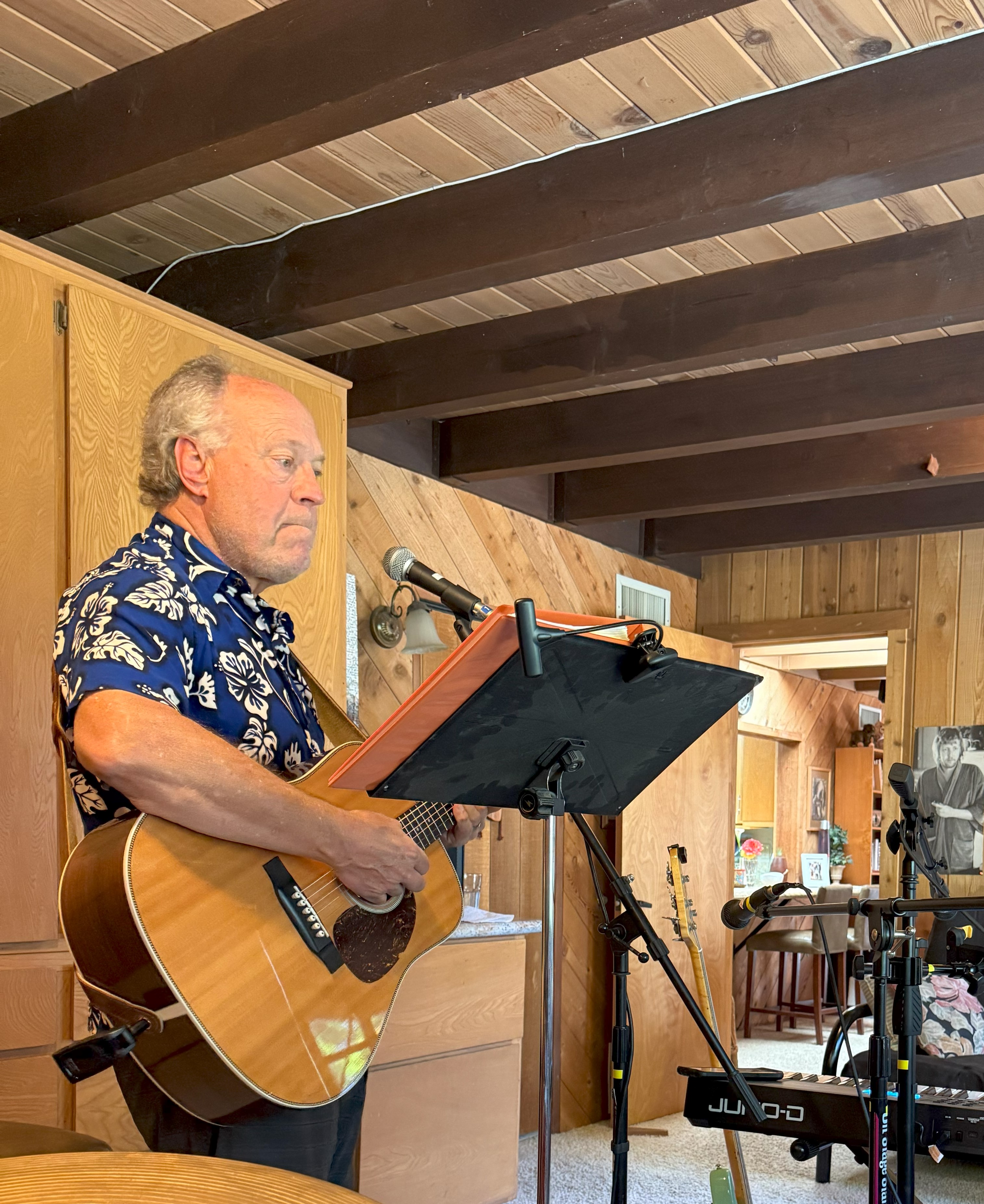 A busy music festival with a drum set and a smiling emoji drum on a close-up perspective in the foreground. An audience wa...